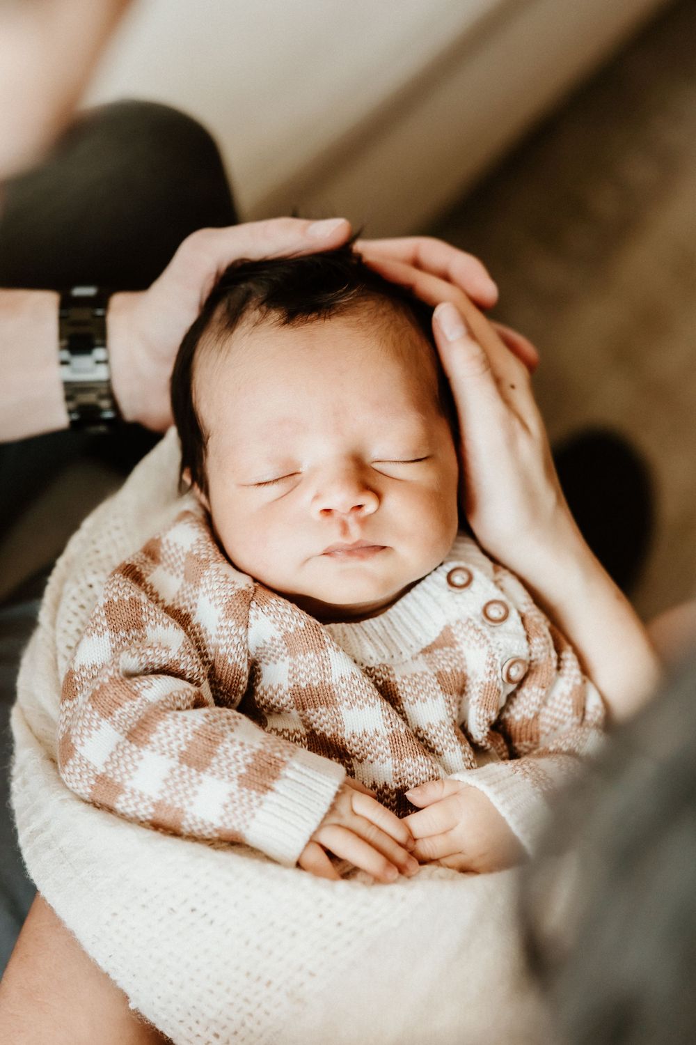 A sleeping newborn baby wrapped in white fabric wearing a soft knitted beige sweater in a collage of closeup shots.