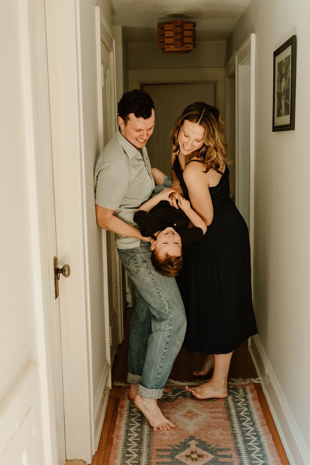 Couple dances together in a dimly lit hallway with pink patterned rugs.
