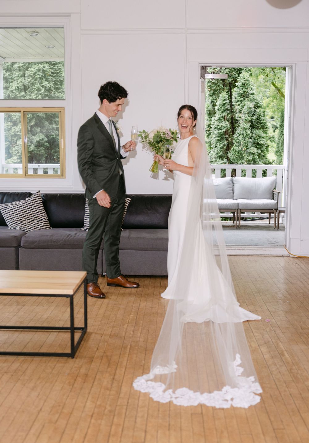 A couple sharing a candid moment in a bright indoor space with large windows and modern decor during their wedding day.