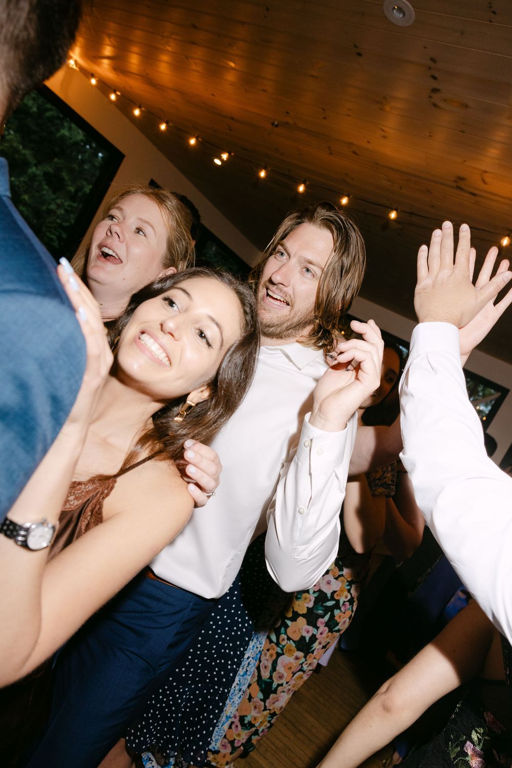 People dancing and enjoying themselves at a lively party with wooden beam ceilings and warm lighting.