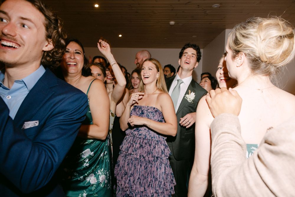 Joyful partygoers dancing and celebrating at an evening event, wearing formal attire including blue suit and sequin dress.