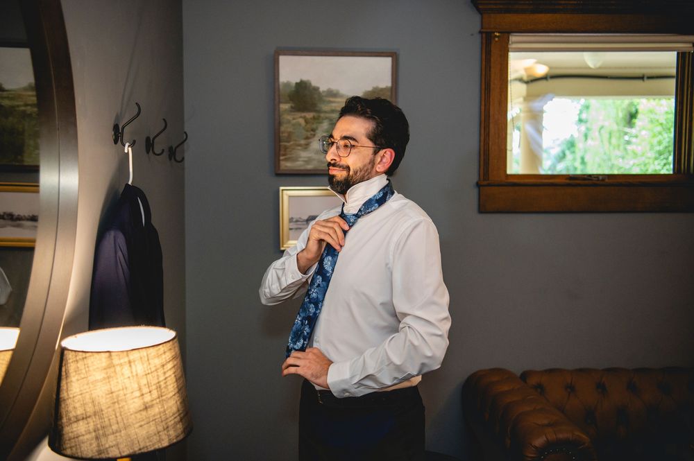 A person in formal attire speaks while holding a microphone during an event at a venue with decorative lighting.