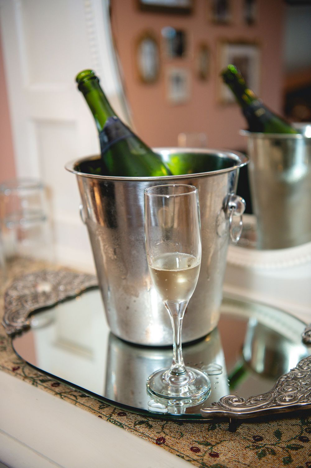 Champagne flutes and green bottles chilling in silver ice buckets on an ornate silver serving tray.