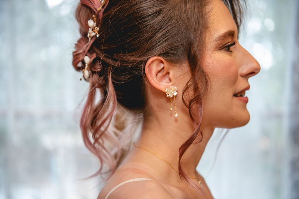 Elegant updo hairstyle with delicate pearl earring seen in side profile against soft bokeh background.
