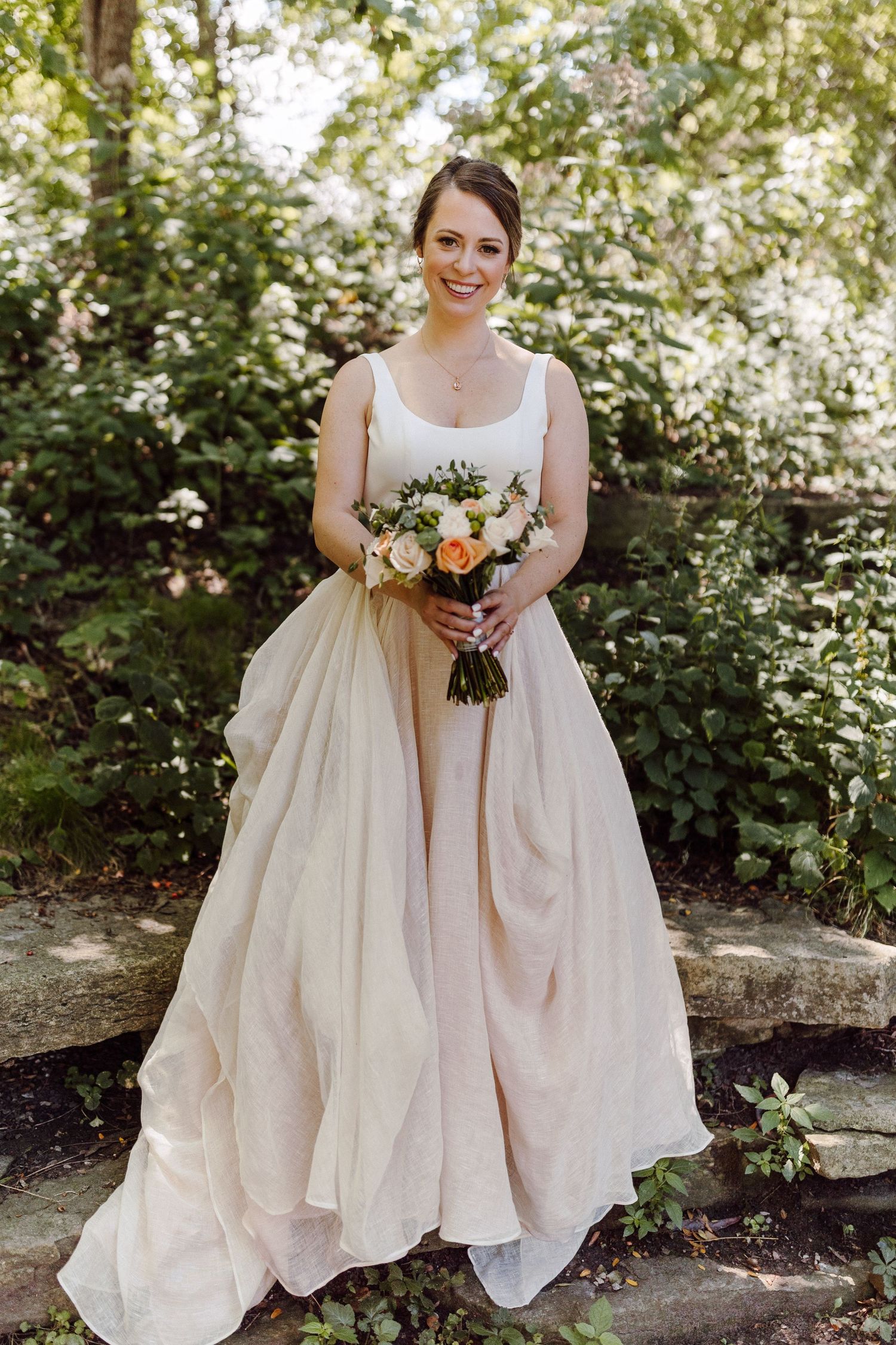 Elegant wedding dress details showing soft cream fabric with delicate folds in a garden setting.