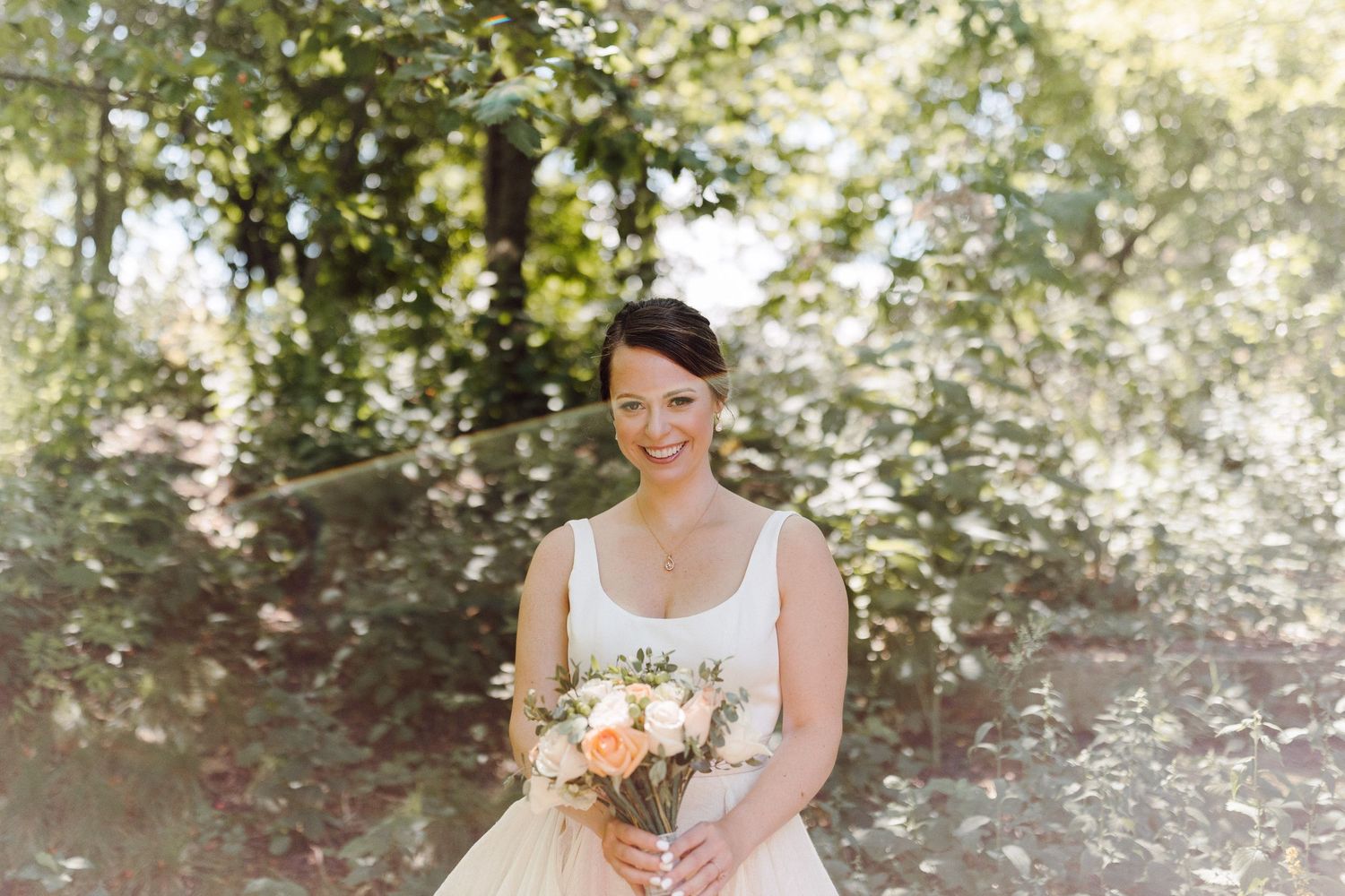 Outdoor bridal portrait with sunlit greenery creating a romantic garden atmosphere.