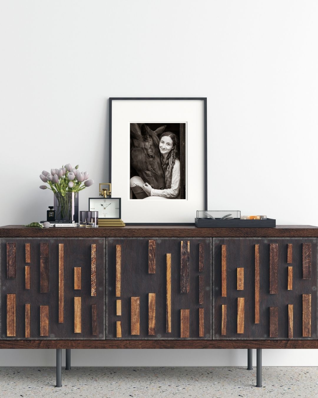 A mid-century modern credenza with geometric wood pattern and metal base styled with vintage decor and framed art.