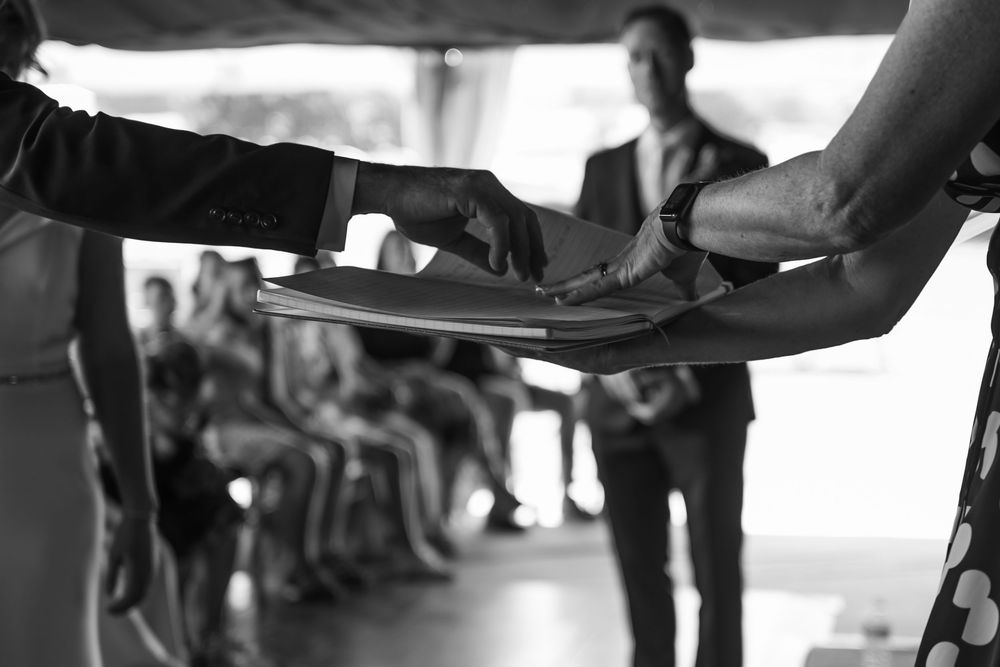 Black and white image of hands passing plates during a catered event service.