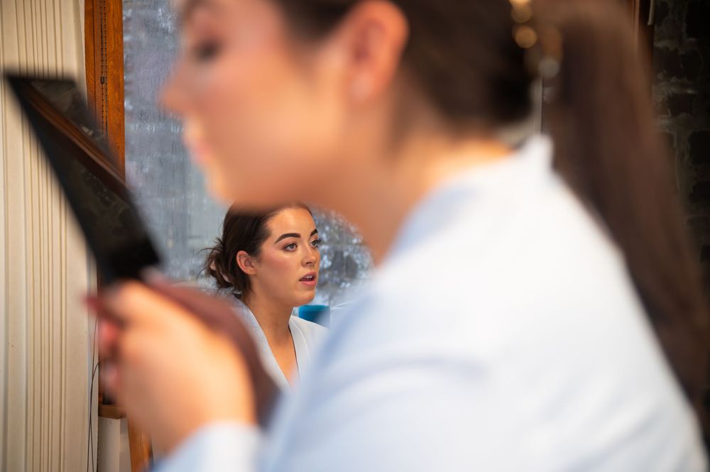 Mirror reflection showing preparation moments before a formal event.
