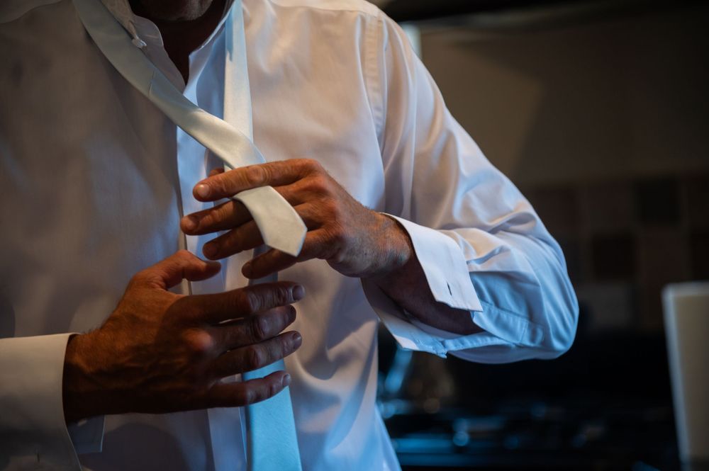 Close-up of hands adjusting formal attire buttons in preparation for an event.
