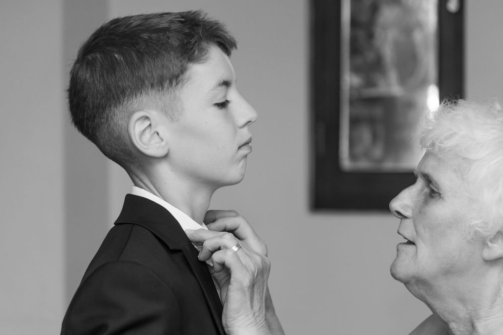 A touching black and white moment of formal tie adjustment before an event.