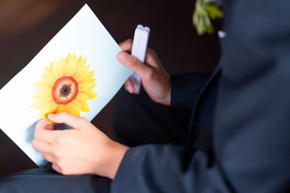 Close-up shot of a sunflower being held by someone wearing blue clothing.
