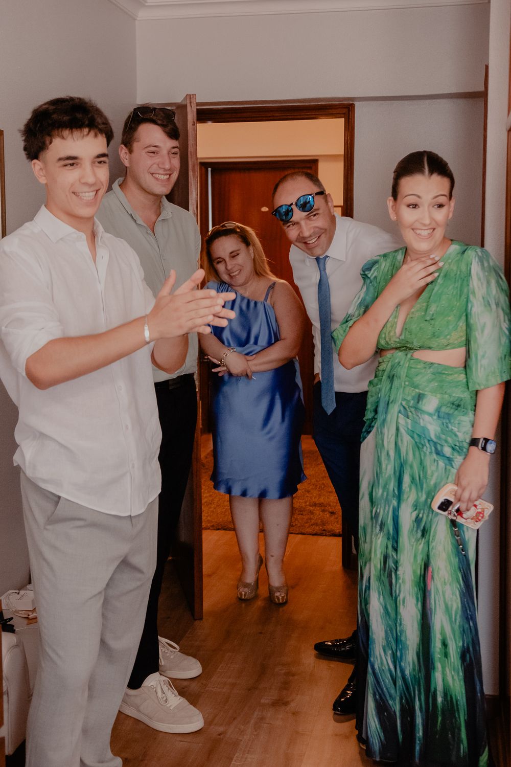 Wedding party members in formal attire pose together, with someone wearing a flowing green dress.