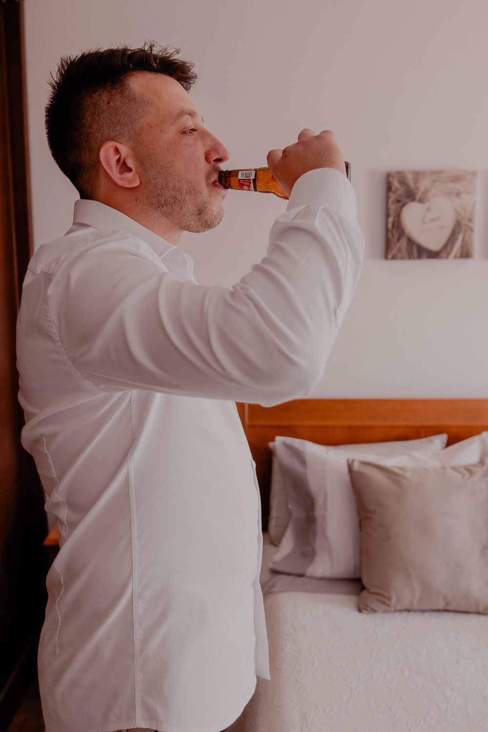 Someone in a white dress shirt adjusts their collar while getting ready.
