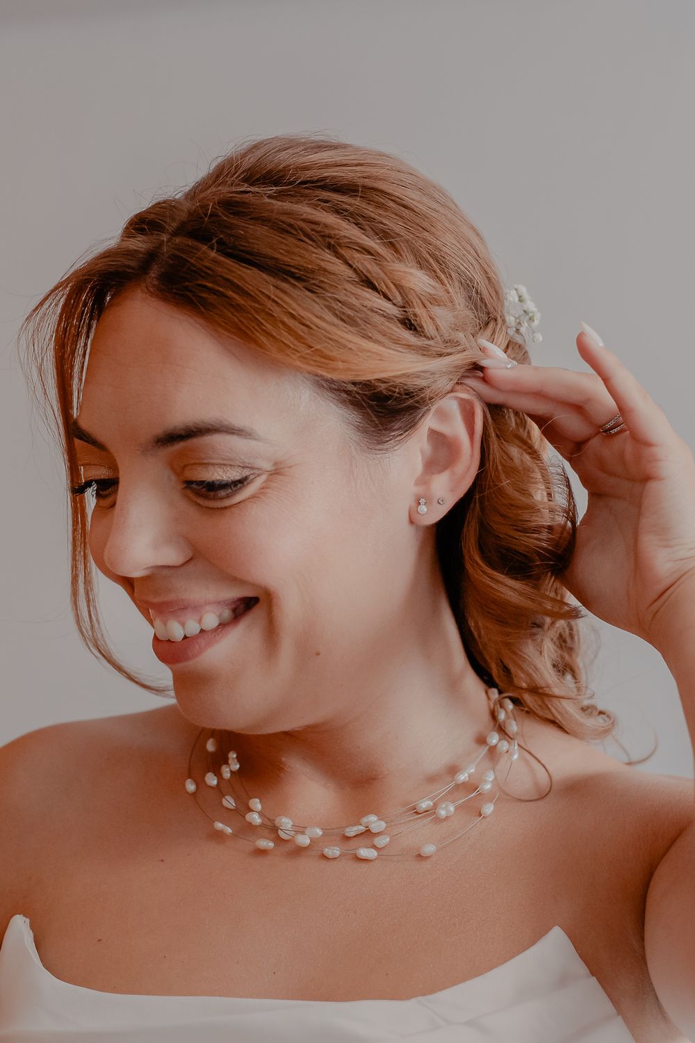 Delicate pearl necklace and earrings complement a strapless white wedding dress.