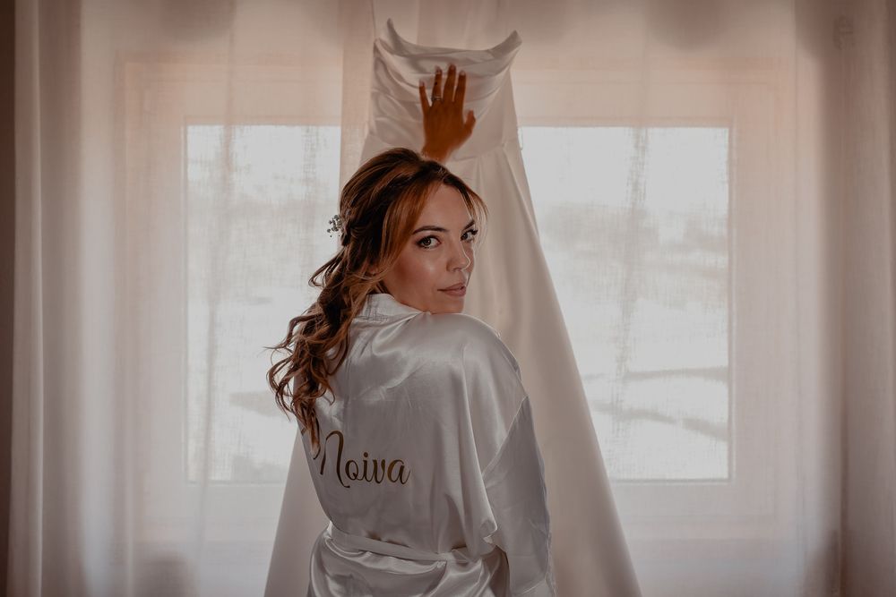 A person in a white robe getting ready in front of a window with soft natural lighting.