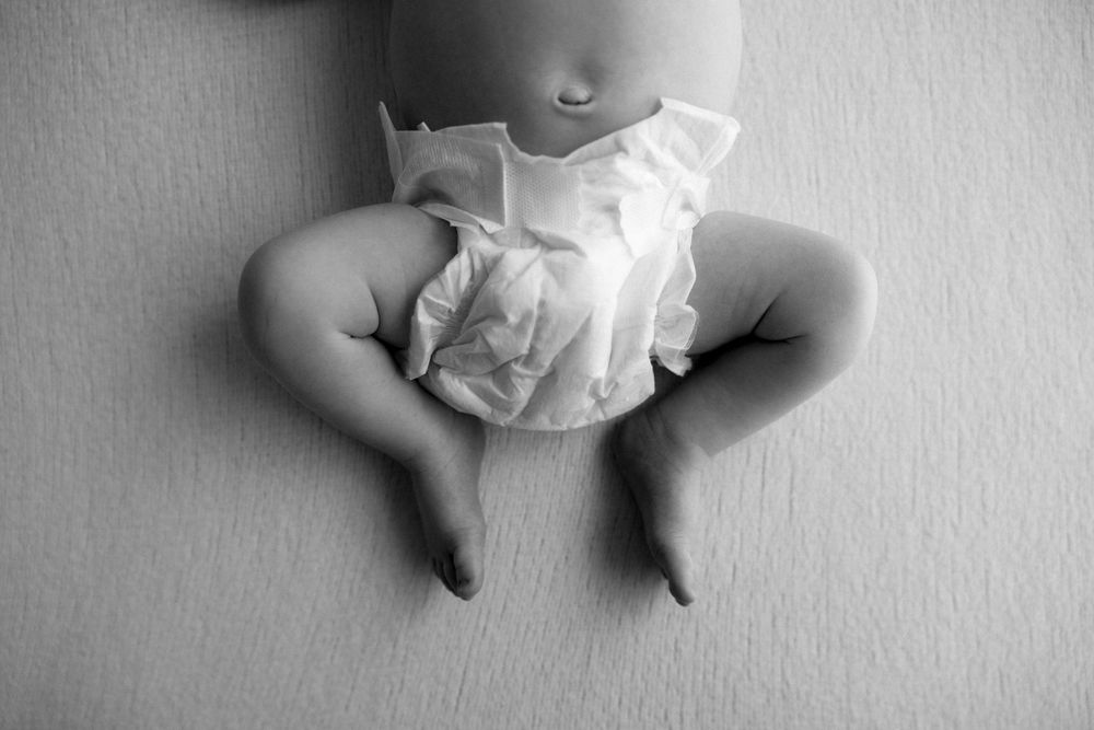 A soft black and white montage of baby feet in different poses against a light background.