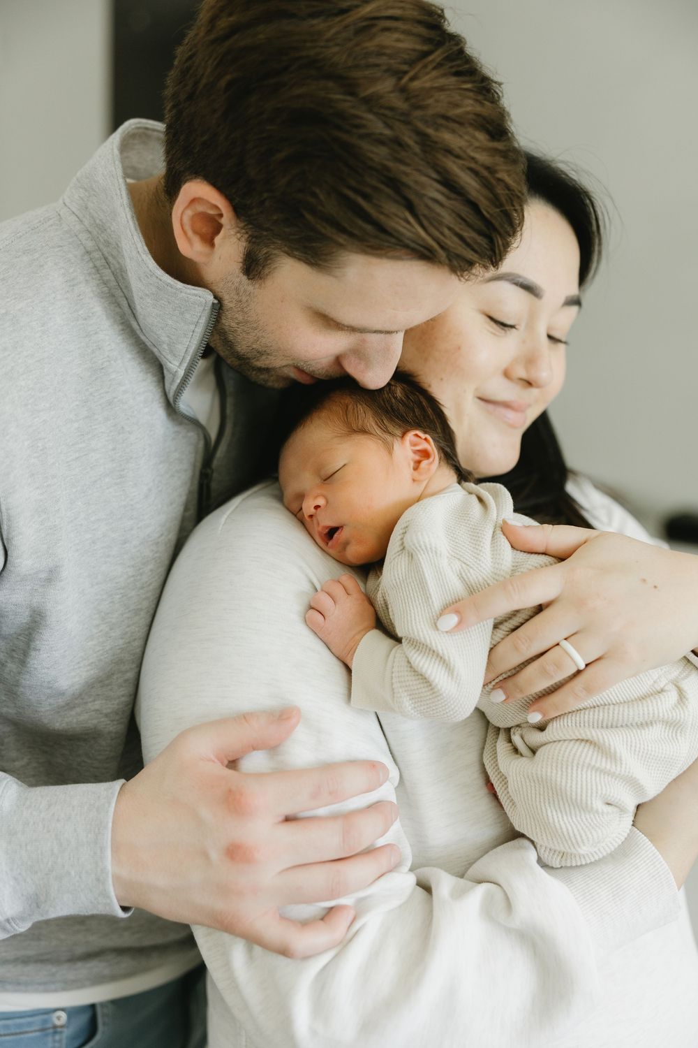 A series of tender moments showing close physical bonding with a young infant in a white outfit.