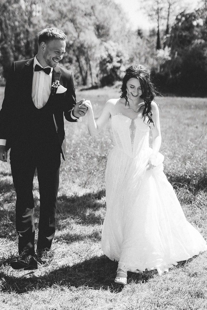 Black and white wedding photos showing a flowing white dress moving in the wind on a sunny outdoor field.