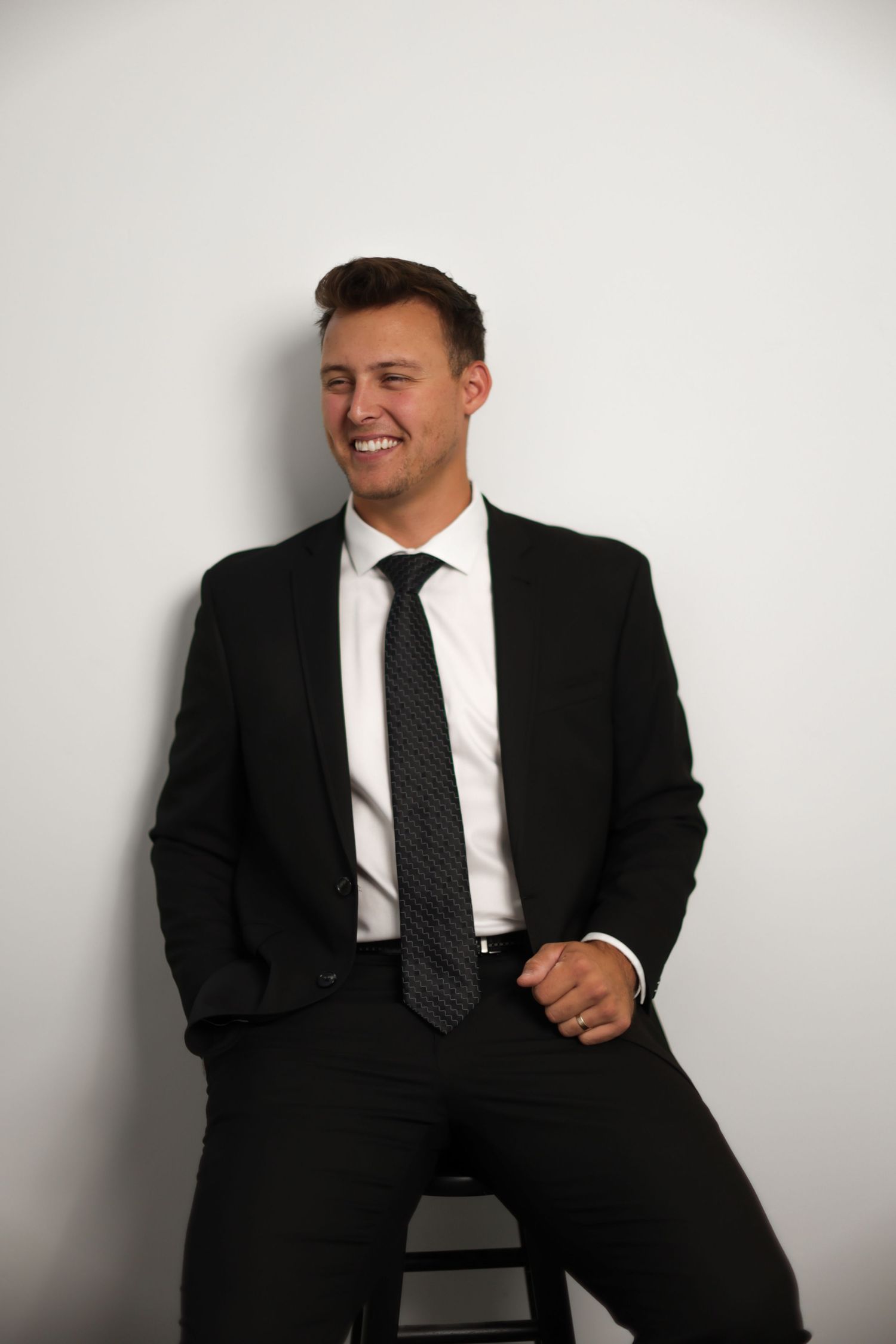Professional in a black suit and tie posing against white background in various candid poses.
