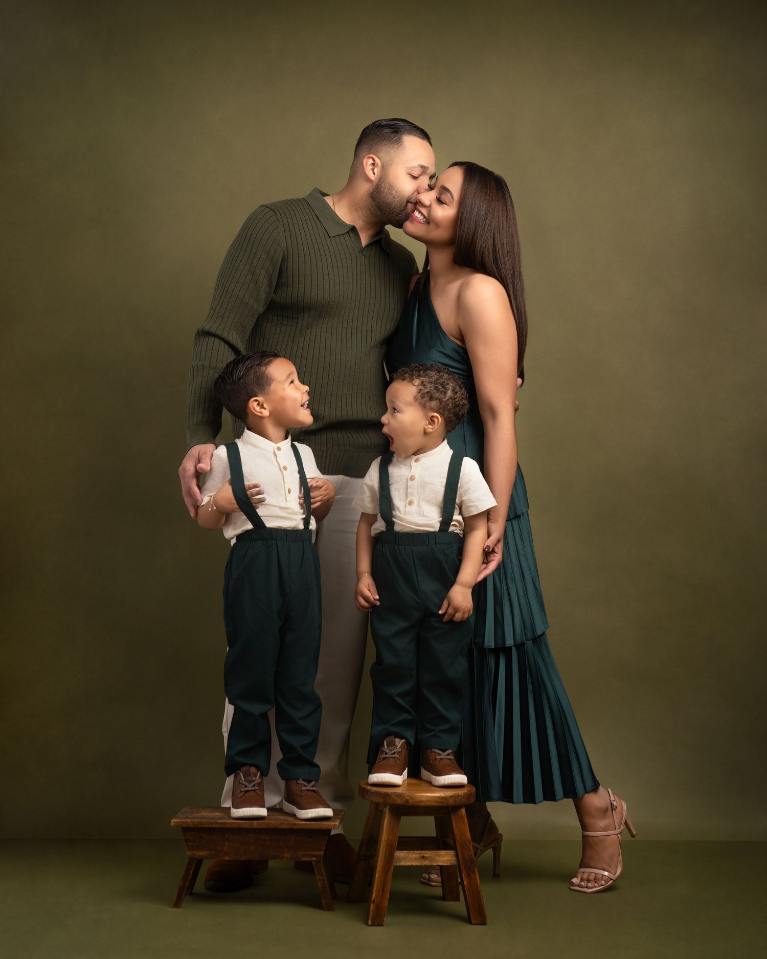Heartwarming portrait series showing a mother and two young children in matching outfits sharing tender moments on wooden stools.