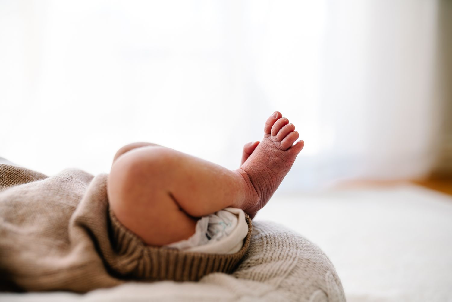 A close-up details of a sleeping baby on soft beige bedding taken by Pei A Photography, a Melbourne newborn photographer.