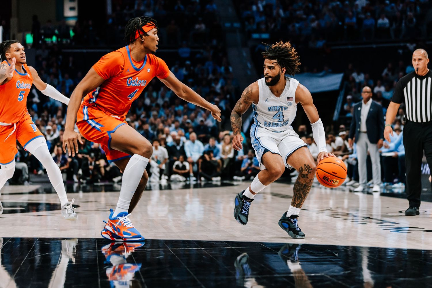 North Carolina Tar Heels guard drives past Florida Gators defender in college basketball game.