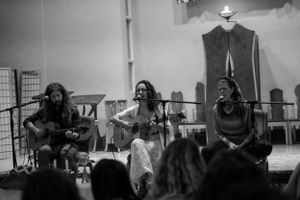 Acoustic performers sing on stage during an intimate concert performance.