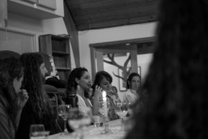 People gathered around a table engaged in lively conversation at a social event.