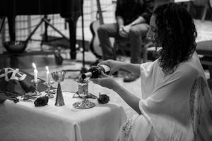 A side view of someone lighting candles on a white tablecloth during a ceremony.