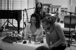 People gathered around a table with drinks and a piano visible in the background.