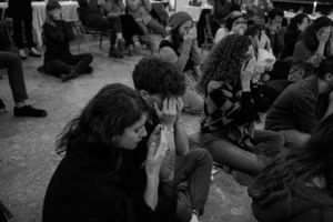A candid black and white shot of people sitting together at a community gathering.