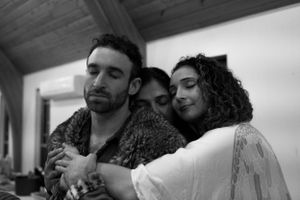 Three people sharing an intimate moment in black and white during a social gathering.