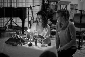 Two people engage in conversation at a candlelit table during an event.