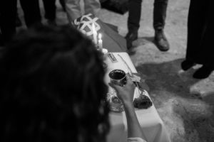 Hands light a ceremonial object releasing smoke during a ritual gathering.