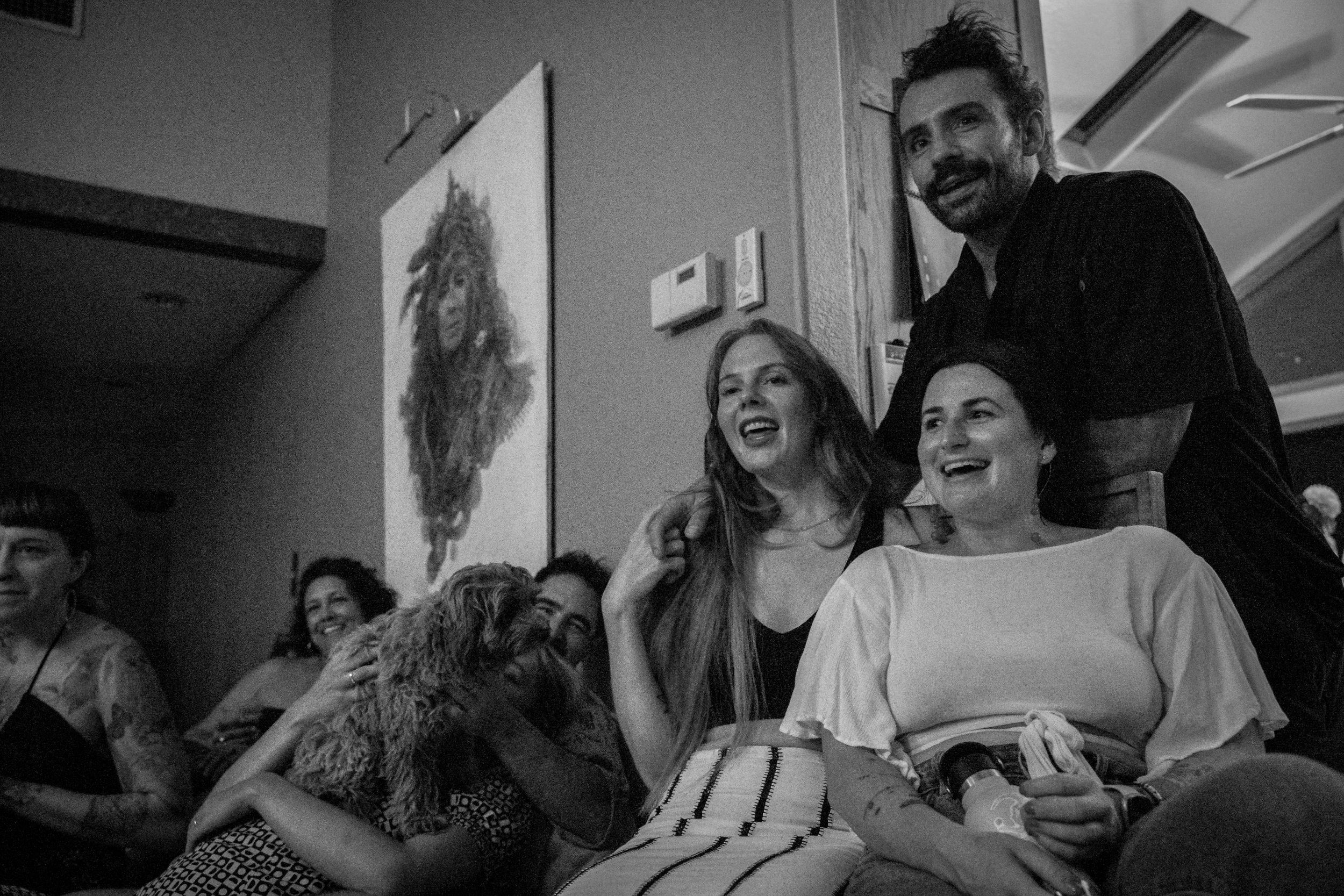 A candid black and white photo capturing laughter and joy during a social gathering.