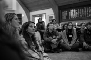 People sitting on the floor during an indoor community gathering.