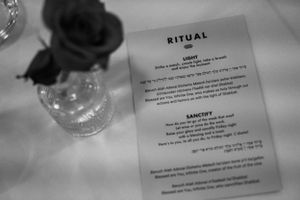 A menu card titled 'RITUAL' sits next to a flower vase on a white tablecloth.