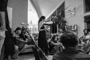 People gather in a living room for an intimate acoustic music performance.