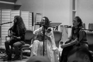 Black and white photo of three musicians performing on stage with instruments.