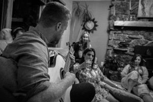 An acoustic guitar performance captivates listeners during an intimate house gathering.