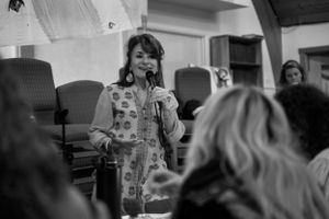 A speaker engaging with an audience in a casual indoor setting.