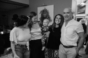 A group poses together for a casual black and white photo at an indoor gathering.