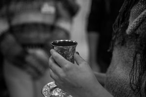 Close-up black and white photo of hands holding an ornate ceremonial cup.