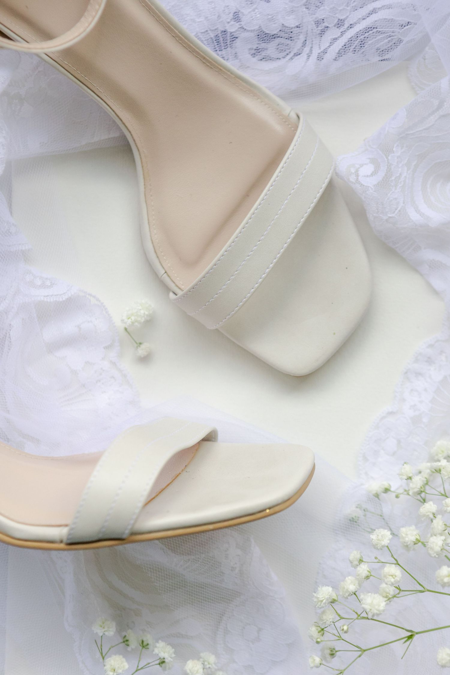Faded pastel pink hues of floral displays with blush coloured ring box and white bridal shoes