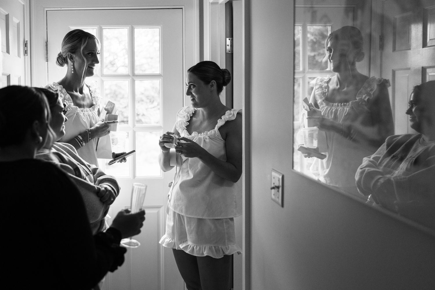 Black and white photo showing silhouettes preparing for a wedding by a window.