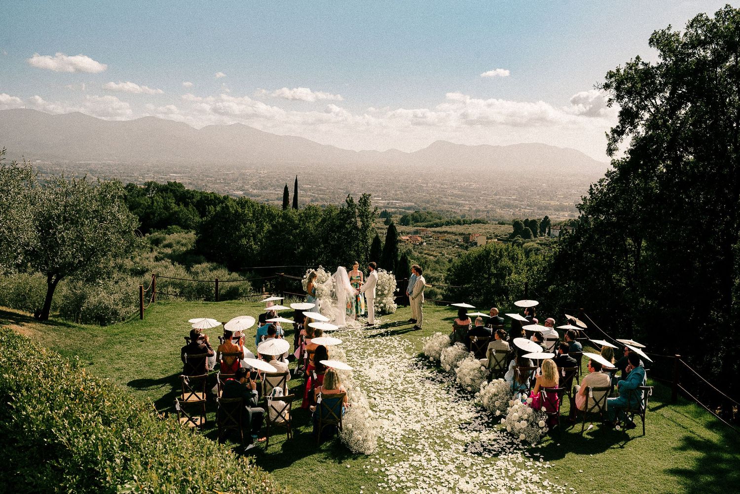 Sweeping views of rolling hills and mountains stretch across a scenic wedding venue in golden afternoon light.