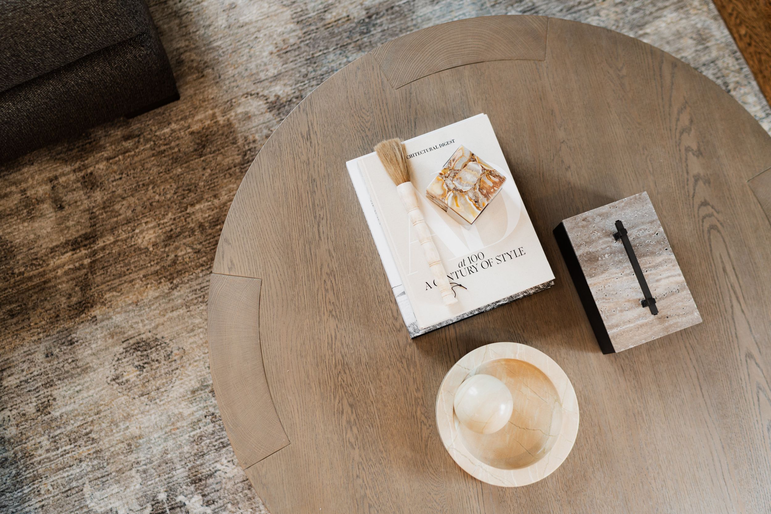 Overhead view of a coffee cup and books arranged on a circular weathered wooden table.