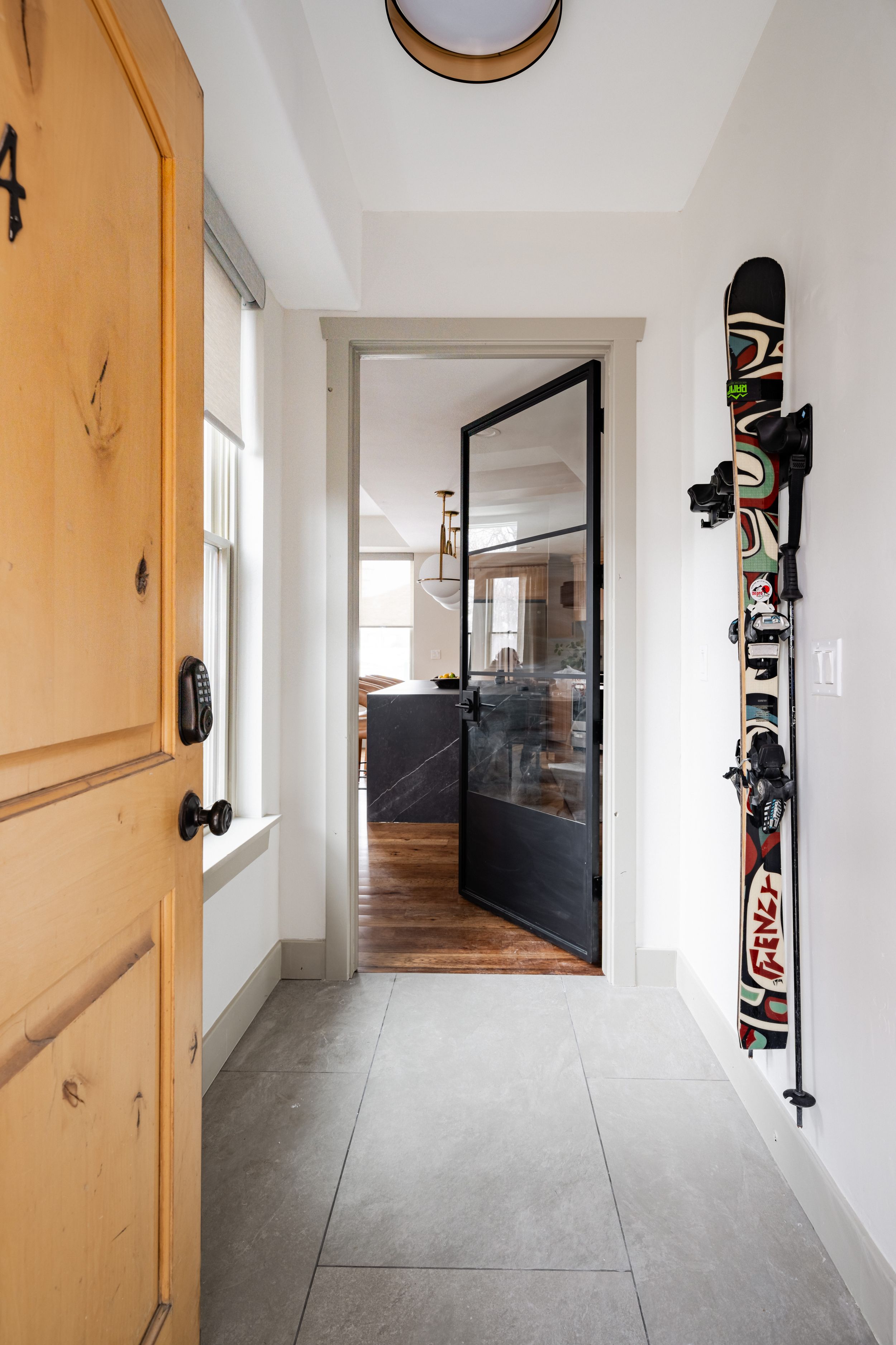 White hallway with mounted ski equipment and wooden doors showcasing modern interior storage solutions.