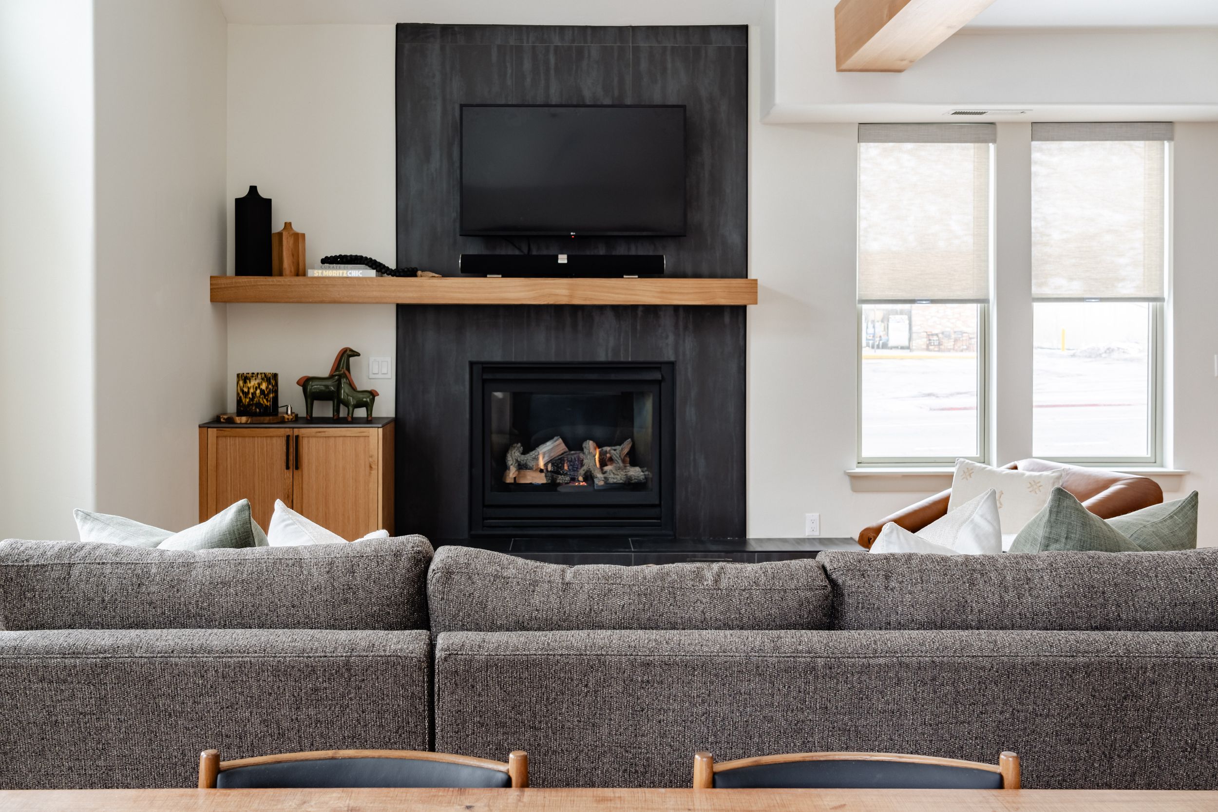 Modern living room features a sleek black fireplace with mounted TV above and gray sectional sofa in contemporary design.